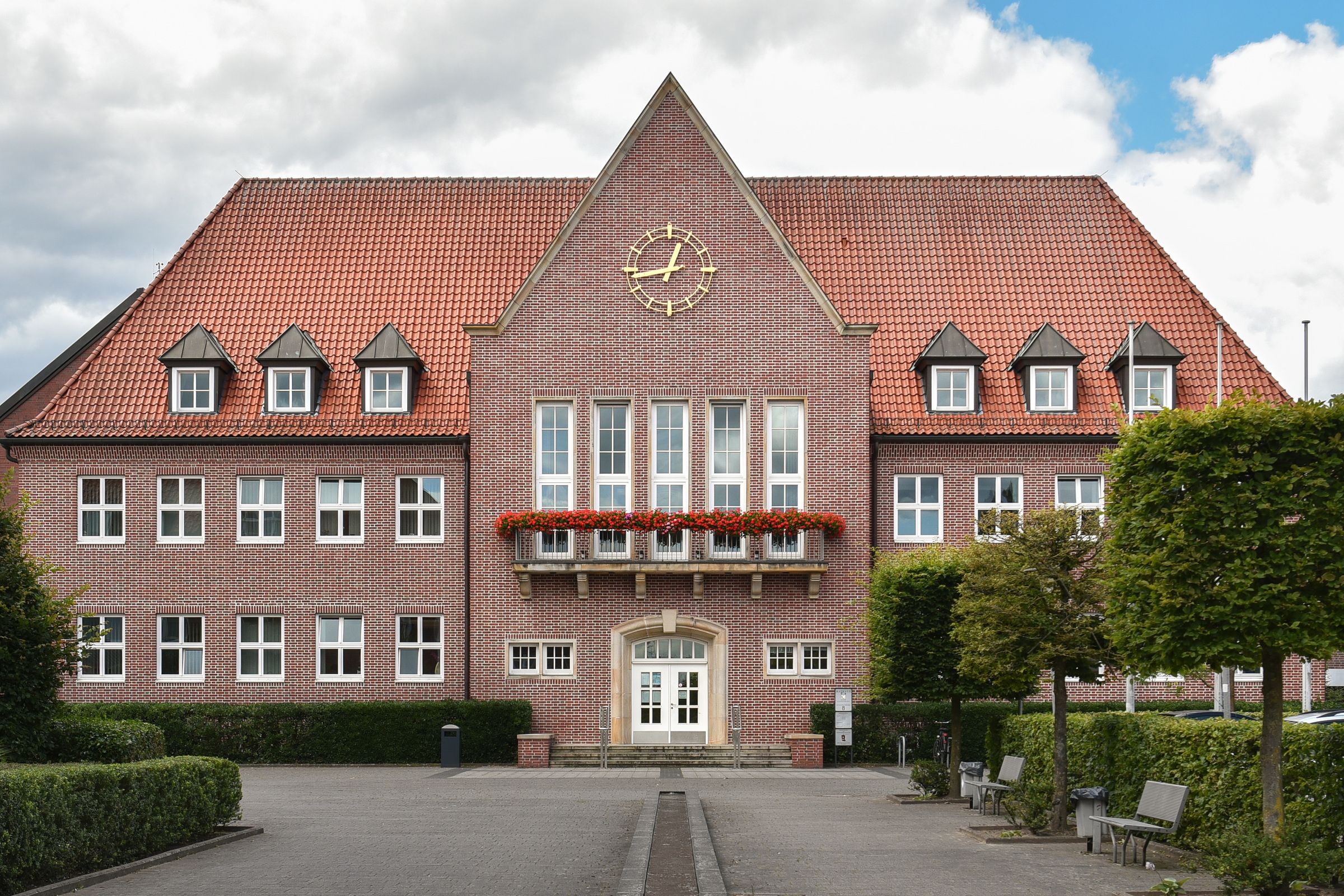 Das Rathaus in Cloppenburg mit Backsteinfassade, Blumenschmuck und begrüntem Vorplatz.