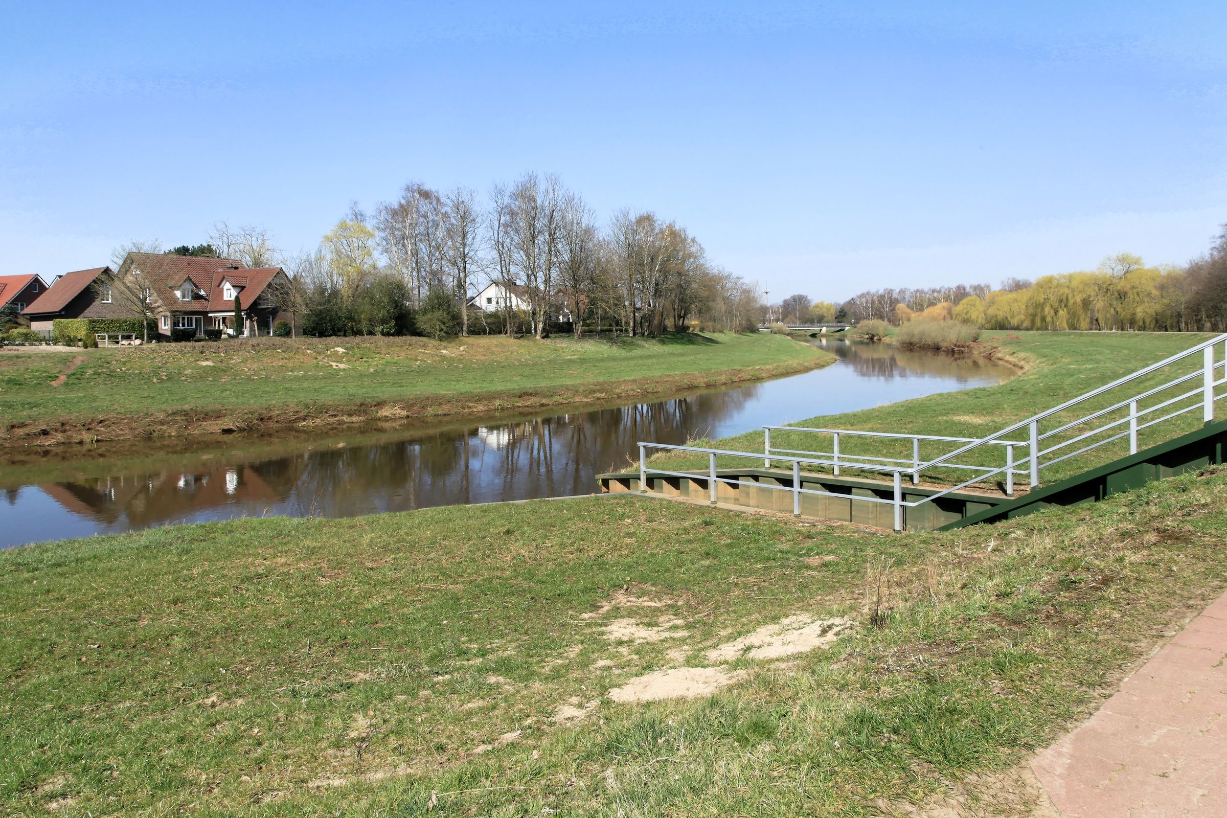 Häuser und Bäume am Ufer der Hase in Haselünne mit einer Treppe zum Wasser.
